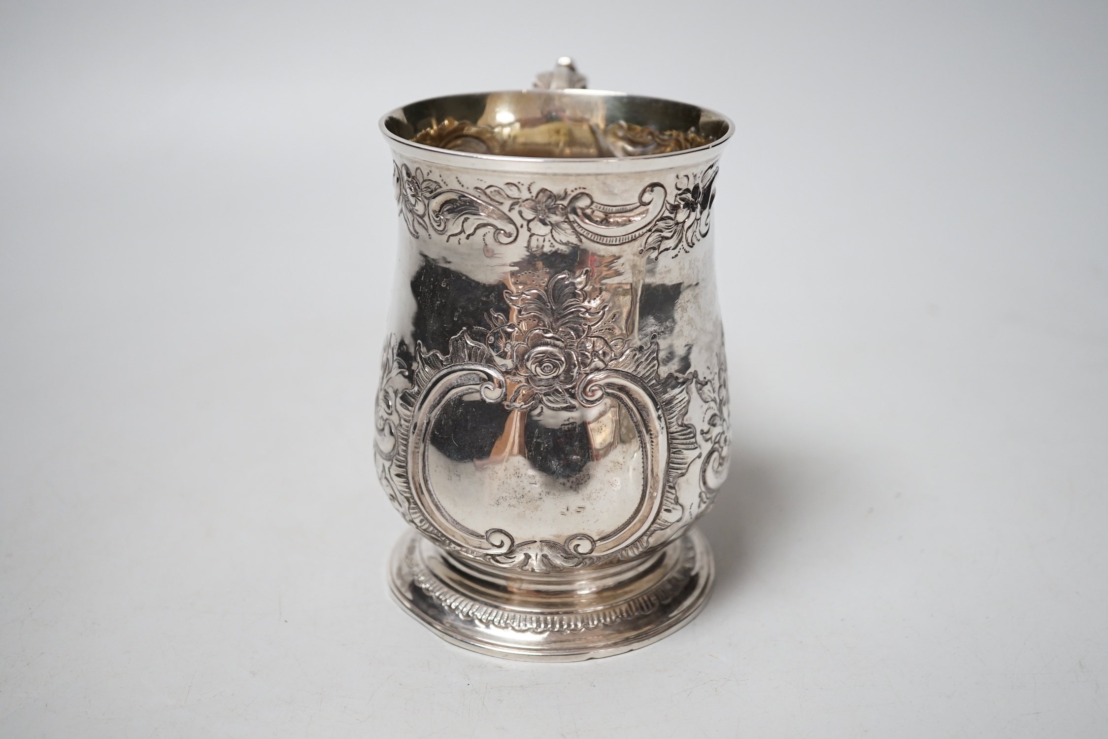 A George III silver mug, with late embossed decoration, John Scofield, 1772, 11.7cm, 9.9oz.